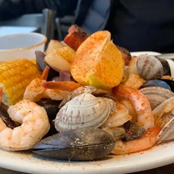 A seafood boil with shrimp, clams, mussels, corn on the cob, and lemon wedges.