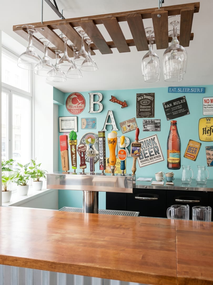 A bar with beer taps, a wooden counter, and a light blue wall decorated with various beer signs.